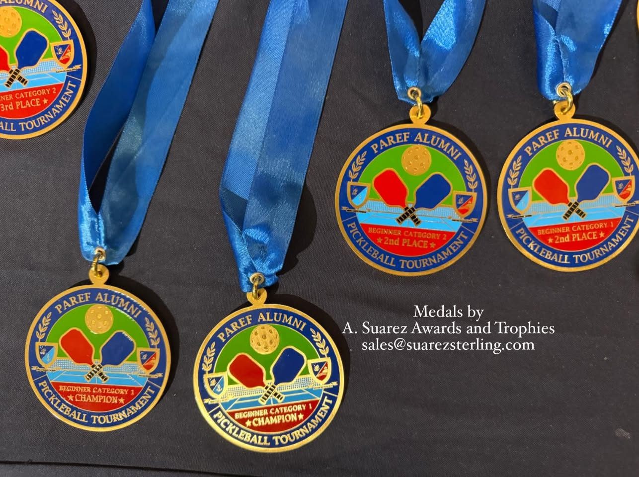 Champion and second place pickleball medals laid out on dark cloth